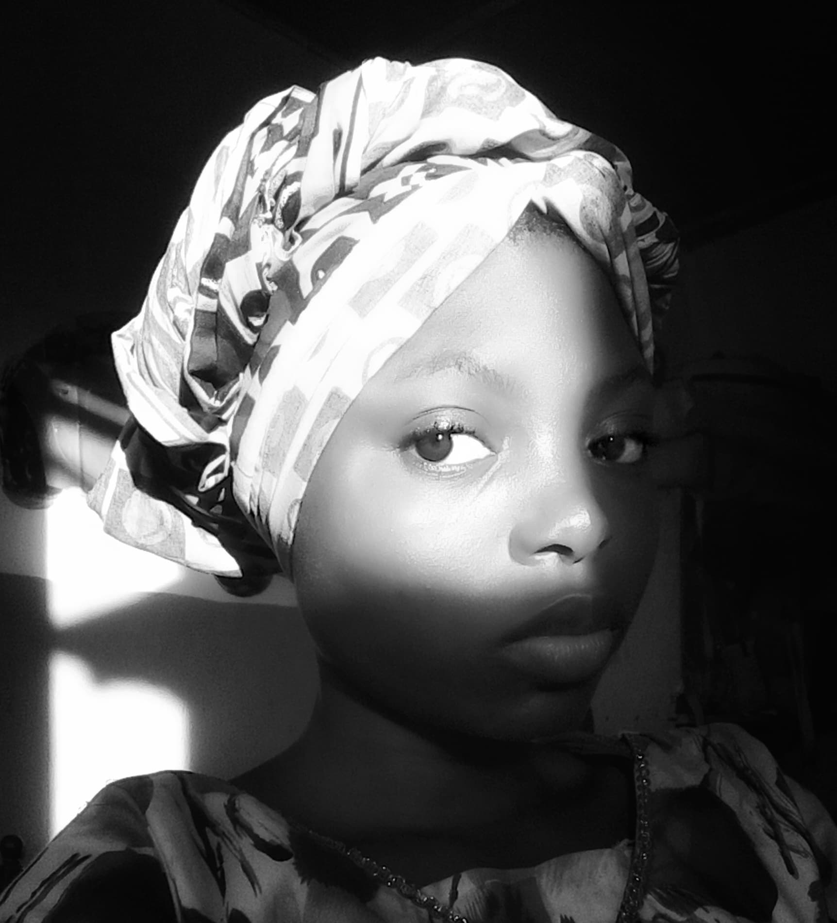 The picture shows a young girl gracefully seated with face lit up with the sunrays. At the background, there is darkness enhancing a balance. In the world today, we experience the bright and dark side of life.